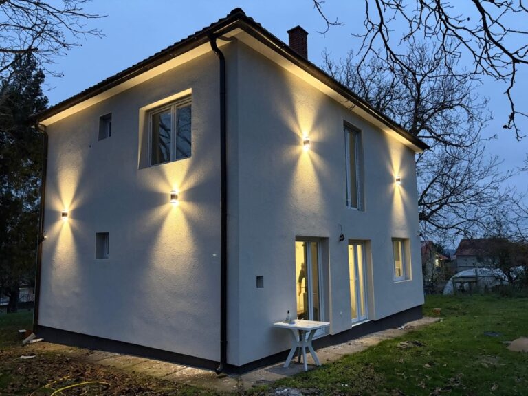 The renovated house at dusk with its outside lights on