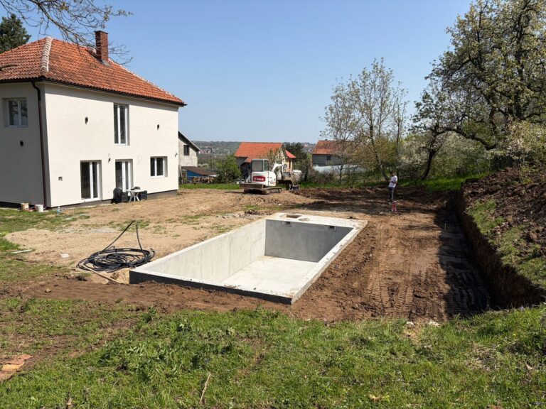 The yard dug up during the works, with the concrete pool shell in front of the house